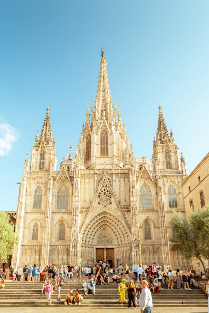 Stunning gothic architecture of Cathedral of Barcelona surrounded by tourists on a bright day.