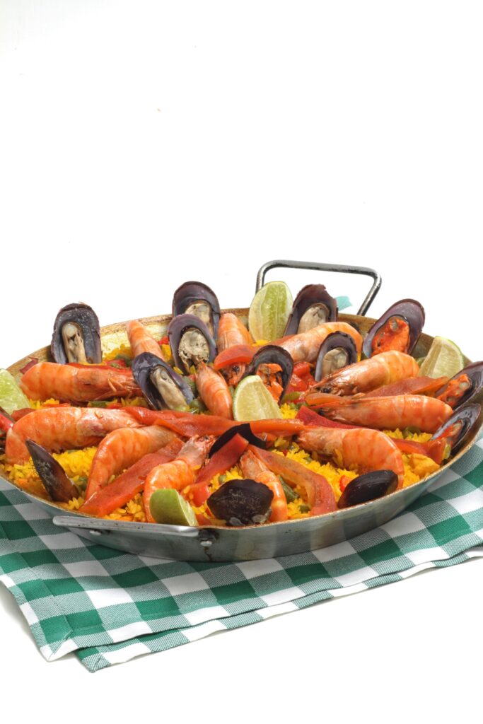 A mouthwatering seafood paella garnished with shrimps and mussels on a white background.