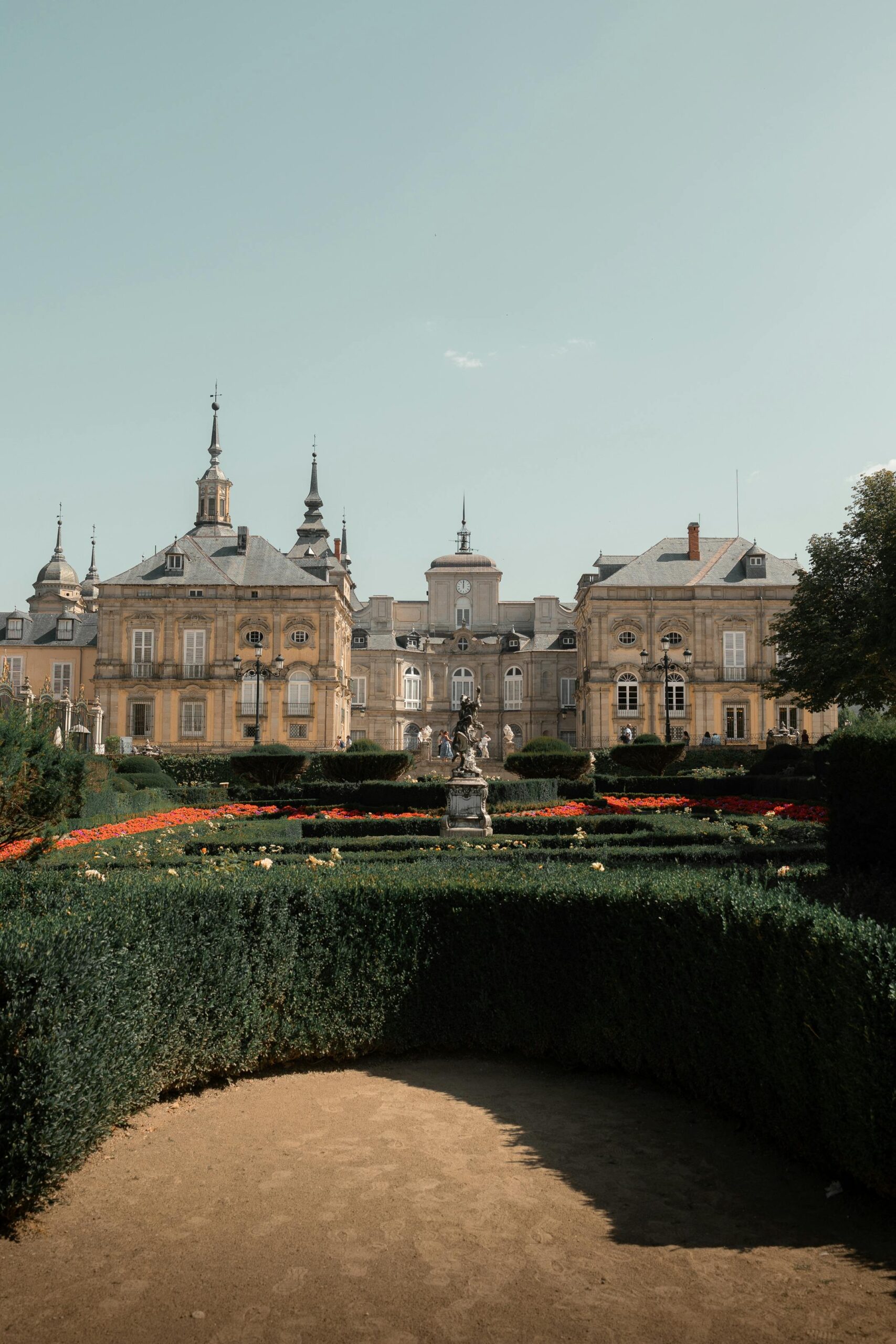 Explore the grandeur of Segovia Palace, Spain, surrounded by meticulously maintained gardens under a clear sky.